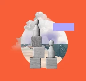 Two wooden peg figures stand on stacked blocks at different heights, set against a circular backdrop with clouds and ocean, on an orange background.